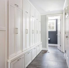 an empty hallway with white cabinets and drawers