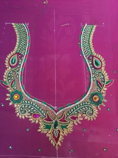 an elaborate necklace is displayed on a pink surface with green and gold beads, surrounded by jewels