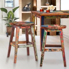 two colorful stools sitting next to each other in front of a table with flowers on it