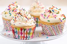 cupcakes with white frosting and sprinkles on a plate