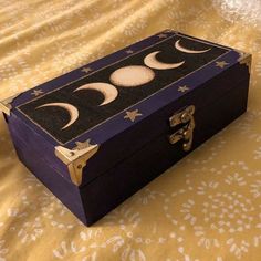 an open box sitting on top of a bed with the moon and stars painted on it