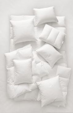 white pillows and pillow cases laid on top of each other