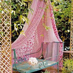 an iron bed frame covered in pink crocheted fabric and flowers on the ground