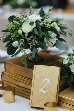 a table topped with books and vases filled with white flowers on top of each other