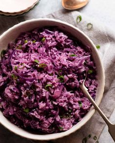 a white bowl filled with red cabbage on top of a table next to a glass of water