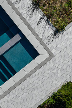 an aerial view of a swimming pool in the middle of some grass and bushes, looking down on it