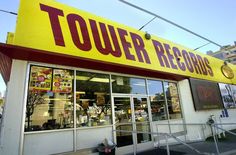 a yellow sign that says tower records on the side of a store front window with stairs leading up to it