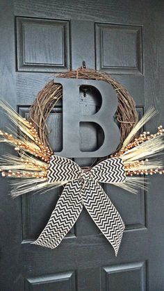 a black door with a wreath and letter b on it's front door, decorated with wheat stalks