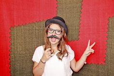 a woman wearing glasses and a fake moustache making the peace sign with her fingers