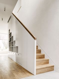 an empty room with white walls and wooden steps leading up to the second floor area