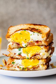 two pieces of toast with eggs and cheese stacked on top of each other in front of a glass of orange juice