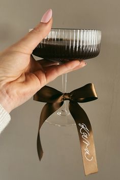 a hand holding a wine glass with a ribbon around it