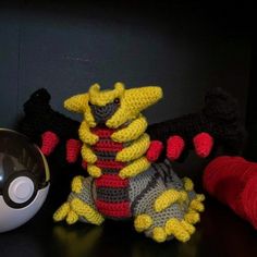 a crocheted toy sitting next to a ball of yarn and a pokeball