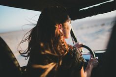 a woman driving a car on the beach