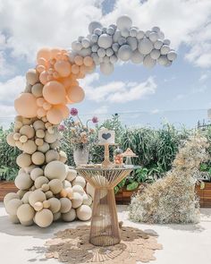 a table topped with lots of balloons on top of a lush green field covered in flowers