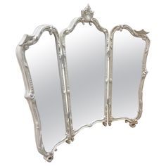 an ornately decorated white mirror with three mirrors on the top and bottom half of it