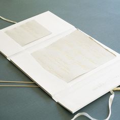 two pieces of white paper with gold writing on them sitting on a table next to a pair of scissors