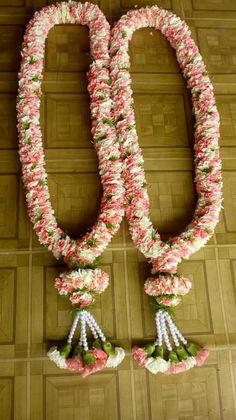 two necklaces made out of flowers and pearls on a wooden floor with tiles in the background