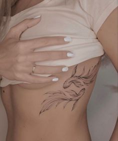 a woman's stomach with a tattoo on her left side, and an image of a goldfish