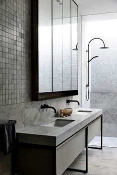 a bathroom with two sinks and mirrors in the wall, along with an open shower