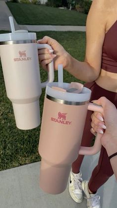 a woman is holding a pink tumbler with a straw in it while another person holds the cup