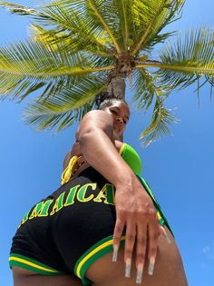 a man in black and green trunks standing under a palm tree with his hand on the back of another mans head