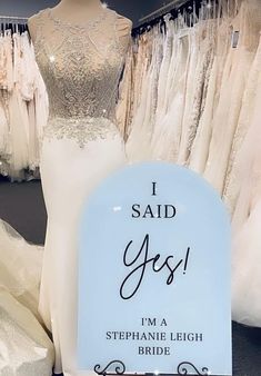 there is a sign that says i said yes in front of some dresses on display