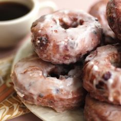 a plate full of glazed donuts next to a cup of coffee