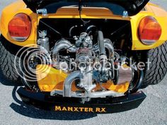 the rear end of a yellow sports car with its hood up and exhaust pipes exposed