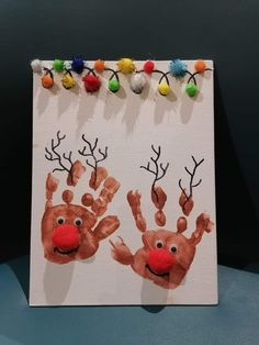 an art project with handprints of two reindeer's and one red nose