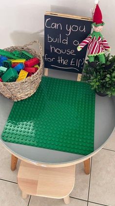 a green lego table with a sign that says can you build a house for the elf?