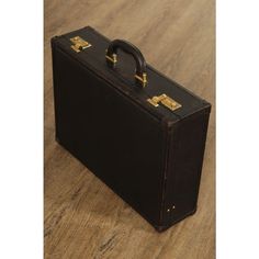 an old black suitcase sitting on top of a wooden floor