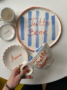 someone is holding a coffee cup and saucer in front of a plate with the words tutto bene on it