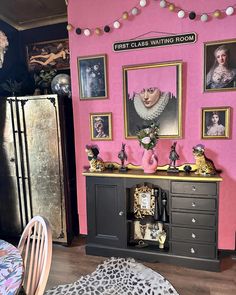 a room with pink walls and pictures on the wall, including an old fashioned dresser