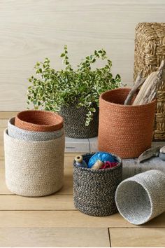 three baskets with plants in them sitting on a wooden floor next to a basket and planter