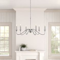 a chandelier hangs over a fireplace in a white room