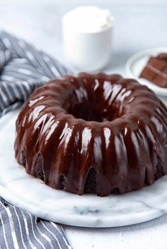 a chocolate bundt cake on a marble plate with a striped napkin next to it