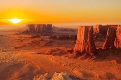 the sun is setting over some rocks in the middle of the desert with sand on them