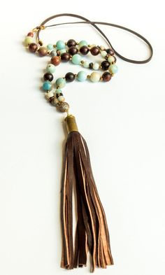 Amazonite, gold hematite, wood beads and brown leather cord with micro pave' bead and repurposed brown lambskin bullet shell tassel. Necklace is approximately 35". Looks great with our Amazonite Tibetan Agate Bracelet Set which is sold separately. All of our tassels are handmade from leather remnants sourced from upholstery and garment factories. Every item sold plants a tree through our partnership with One Tree Planted. Pyrite Bracelet, Bullet Shell, Pave Beads, Hematite Bracelet, Gemstone Beaded Bracelets, Agate Bracelet, Trendy Necklaces, Shell Jewelry, Agate Gemstone