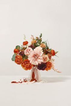 a bouquet of flowers on a white background with red, orange and pink blooms in the center