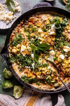 a skillet filled with corn, cheese and herbs