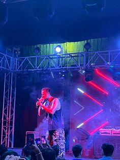 a man standing on top of a stage holding a microphone in front of a crowd