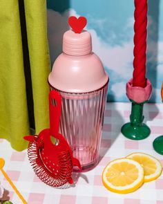 a table topped with oranges and lemon slices next to a pink cup filled with liquid