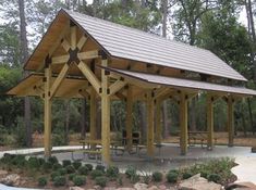 a pavilion with picnic tables and benches in the middle of a wooded area surrounded by trees