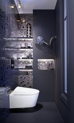 a modern bathroom with black and white mosaic tiles on the walls, along with a toilet