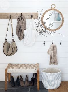 a white bench sitting under a round mirror next to a wooden shelf with shoes hanging on it