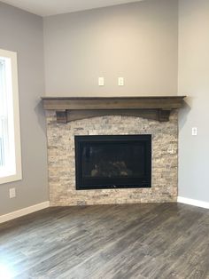 an empty living room with a fireplace and hard wood floor