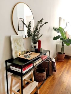 a room with a desk, mirror and potted plant on the side table in front of it