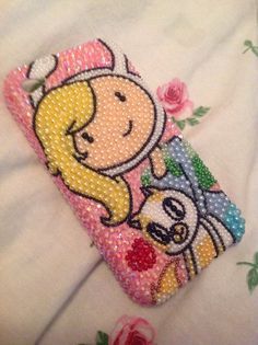 a cell phone case with a cartoon character on the front and side, sitting on top of a flowered sheet