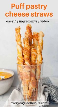 puffy pastry cheese straws in a glass bowl with dipping sauce on the side